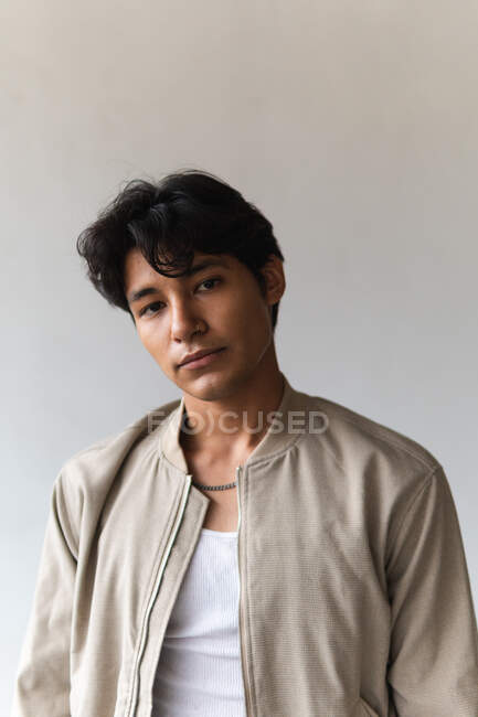 Ritratto di giovane uomo latino che guarda con fiducia la macchina fotografica sullo sfondo neutro — Foto stock