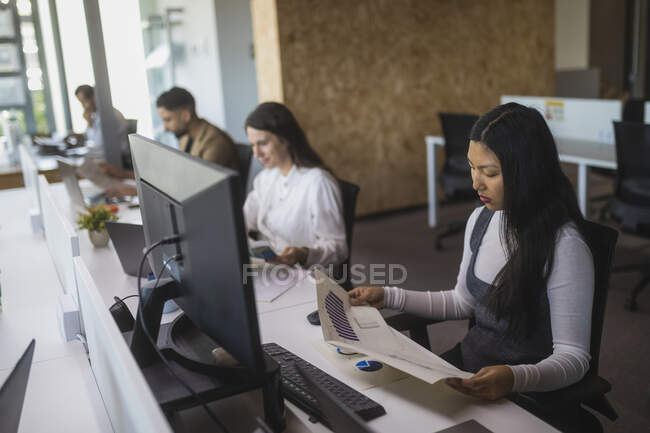 Gruppe fokussierter multiethnischer Kollegen sitzt am Tisch und arbeitet an einem Projekt im modernen Coworking Space — Stockfoto