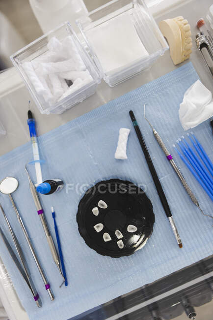 De arriba del frasco con los dientes entre las herramientas surtidas de la ortodoncia en la servilleta contra la mandíbula echada en el hospital - foto de stock