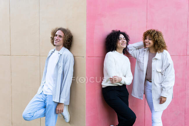 Smiling man and multiethnic women with curly hair standing at colorful walls of corner — Stock Photo