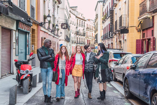 Empresa de amigos multirraciais felizes em roupas elegantes andando juntos na rua da cidade durante o fim de semana — Fotografia de Stock