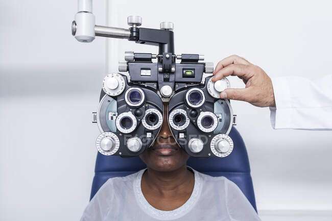 Optometrist beim Einstellen der Optometrie-Ausrüstung während der Untersuchung des Sehvermögens einer schwarzen Frau — Stockfoto