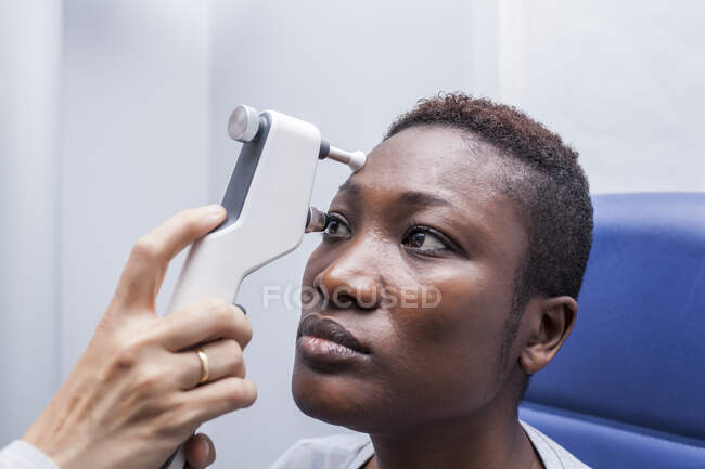 Оптометрист с помощью офтальмоскопа при изучении зрения черной женщины — стоковое фото