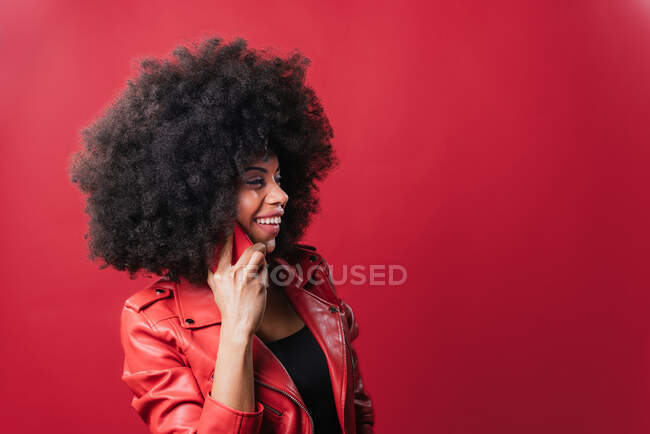 Amazed African American female speaking on mobile phone on red background in studio — Stock Photo