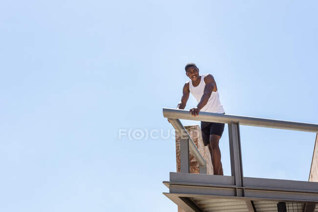 From below of African American fit male athlete standing on terrace — Stock Photo