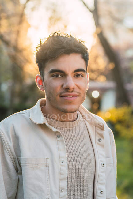 Vista lateral de encantado bonito macho sorrindo enquanto passar fim de semana no parque e olhando para longe — Fotografia de Stock