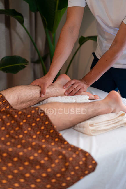 Unrecognizable therapist massaging legs of male client while doing Thai massage in spa center — Stock Photo