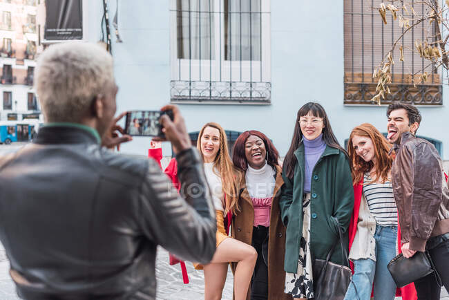 Back view of unrecognizable black male taking photo of company of multiracial friends standing on street together — Stock Photo