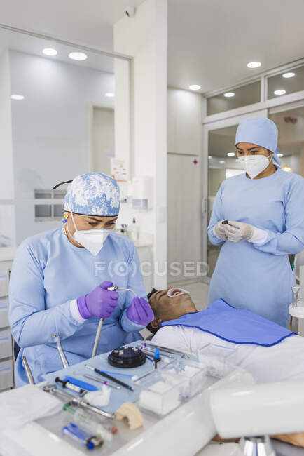Dentiste féminine avec outil de préparation des placages pour l'intervention en clinique — Photo de stock