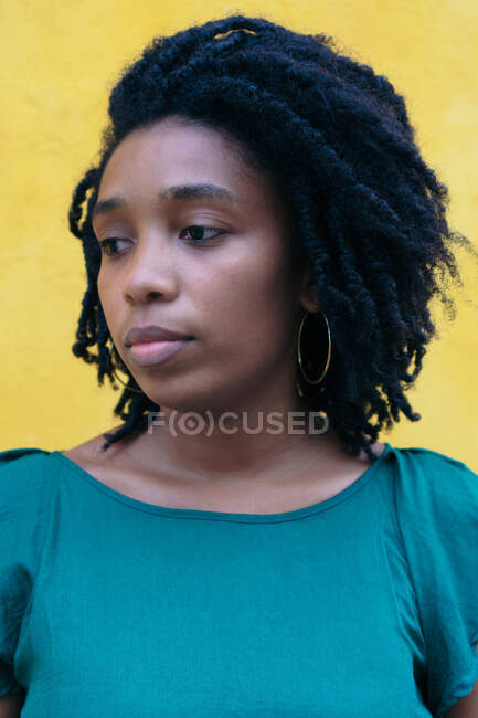 Ritratto di giovane donna nera pensierosa davanti a una parete gialla — Foto stock