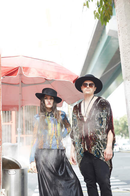 Couple élégant confiant en vêtements hipster debout dans la rue en été et regardant la caméra — Photo de stock