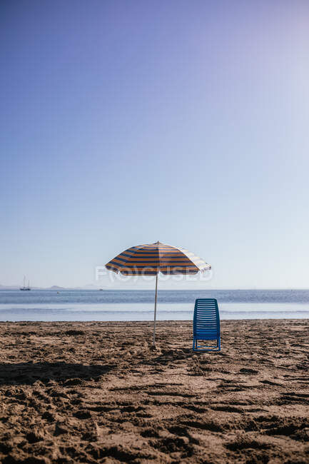 Landschaft Blick auf Sonnenschirm und Stuhl auf Sand am Strand an einem Sommertag platziert — Stockfoto