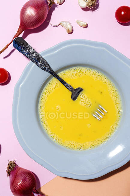 Вид зверху збиті яйця на тарілці проти стиглої червоної цибулі — стокове фото