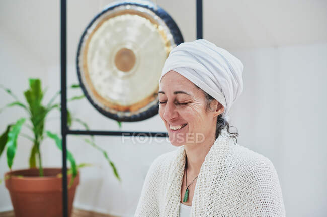 Donna matura con gli occhi chiusi seduto e praticare yoga a casa — Foto stock