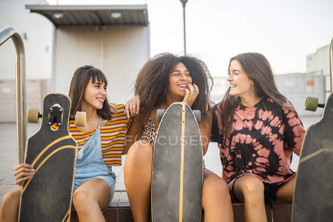 Drei junge Frauen verschiedener Rassen mit ihren langen Brettern haben Spaß und lächeln — Stockfoto