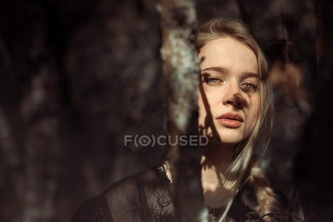 Portrait de jeune belle femme blonde dans une forêt, éclairage dramatique sur son visage — Photo de stock