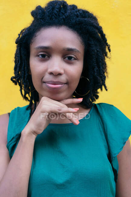 Portrait de jeune femme avec une coiffure afro appuyée contre un mur — Photo de stock