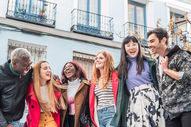 Company of happy multiracial friends in stylish clothes standing at camera together in city street during weekend — Stock Photo