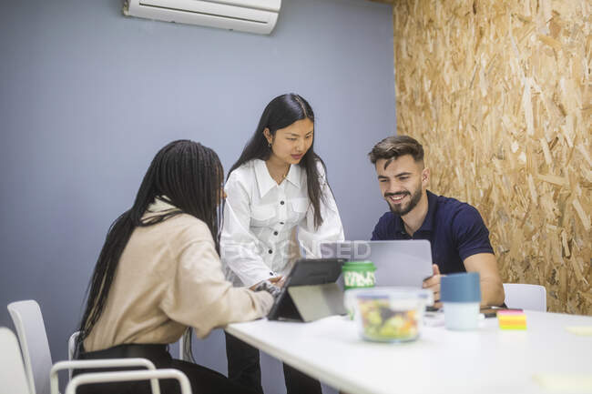 Gruppe multiethnischer Content-Mitarbeiter trifft sich am Tisch und nutzt Geräte während der Arbeit an einem Startup-Projekt — Stockfoto