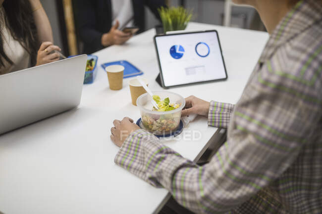 Beschnitten bis zur Unkenntlichkeit Gruppe von unkenntlichen Mitarbeitern, die sich am Tisch versammeln und Mittagessen am Arbeitsplatz essen — Stockfoto