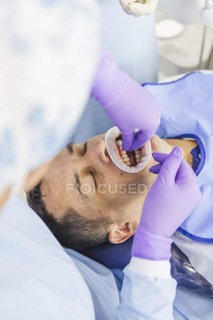 High angle of crop orthodontist in gloves installing dental veneers on teeth for protection during appointment in clinic — Stock Photo