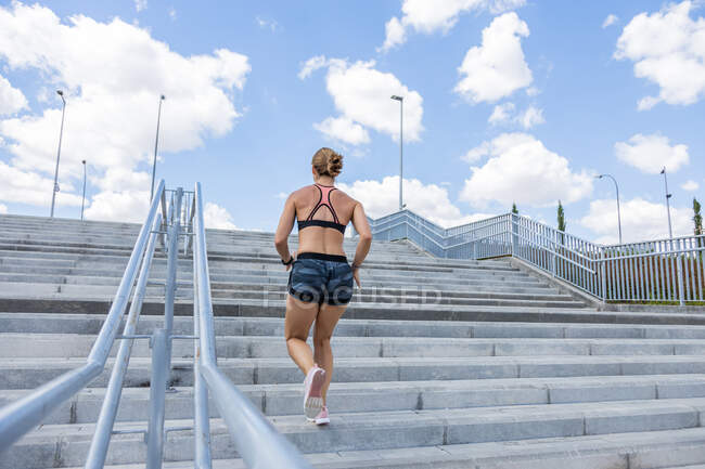 Femme méconnaissable formation pour monter les escaliers à l'extérieur, vue arrière — Photo de stock