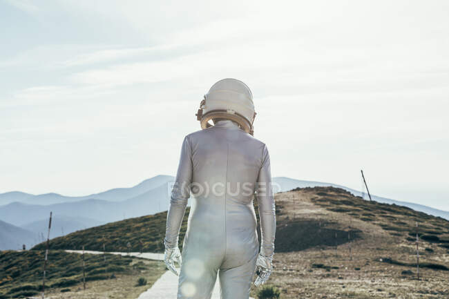 Back view man in spacesuit and helmet looking away while standing on path on sunny day in nature — Stock Photo