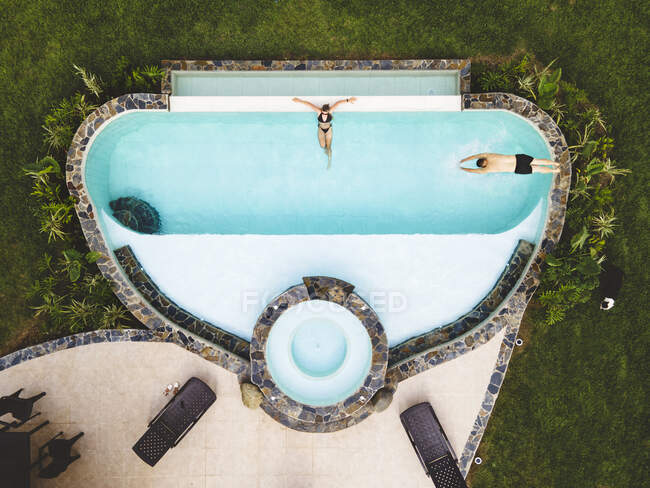 Пара с лучшим видом в бассейне, наслаждающаяся солнечным летним днем — стоковое фото