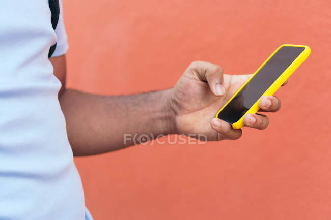 Jovem com telefone inteligente ao lado de uma parede vermelha — Fotografia de Stock