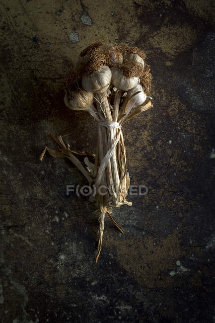 Von oben Strauß frischer lila Knoblauchzehen im dunklen Hintergrund platziert — Stockfoto