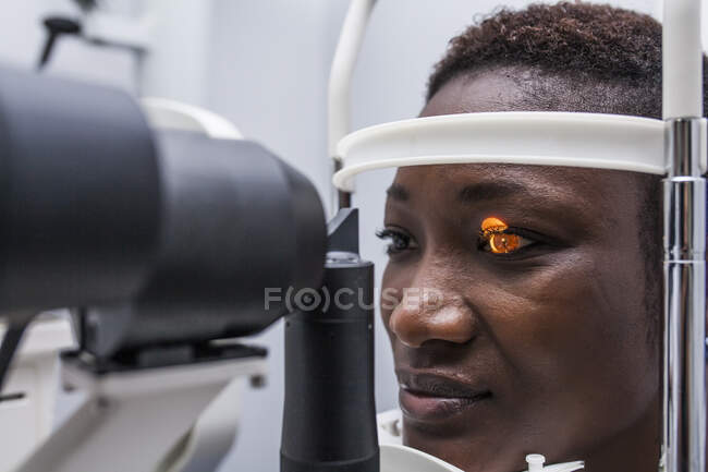Augenoptiker beim Einstellen des Retinographen während der Untersuchung des Sehvermögens einer schwarzen Frau — Stockfoto