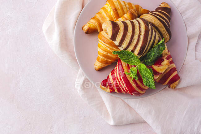 Desde arriba de surtidos cruasanes dulces servidos en canasta en la mesa para el desayuno - foto de stock