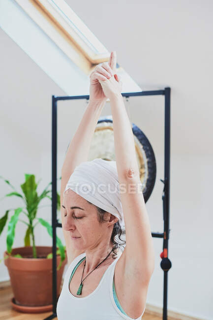 Donna in piedi in posa Vrksasana durante la pratica dello yoga su moquette morbida e occhi chiusi in camera di casa — Foto stock