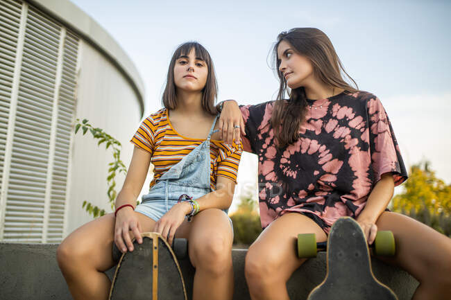 Zwei schöne junge Frauen sitzen in Ruhe und lachen mit ihren langen Brettern — Stockfoto