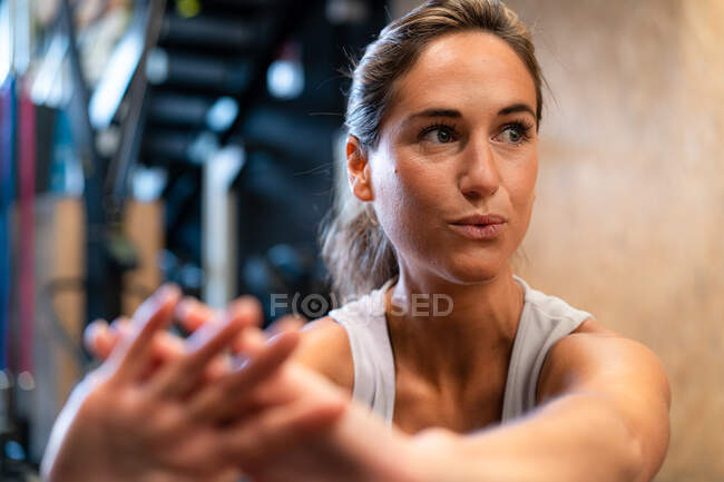 Fit female athlete in sportswear doing exercise in gym looking away — Stock Photo