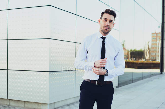 Hombre emprendedor en ropa formal con reloj de pulsera mirando a la cámara en la ciudad - foto de stock