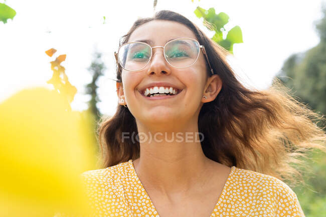 From below delighted female in dress standing in park looking away in summer — Stock Photo
