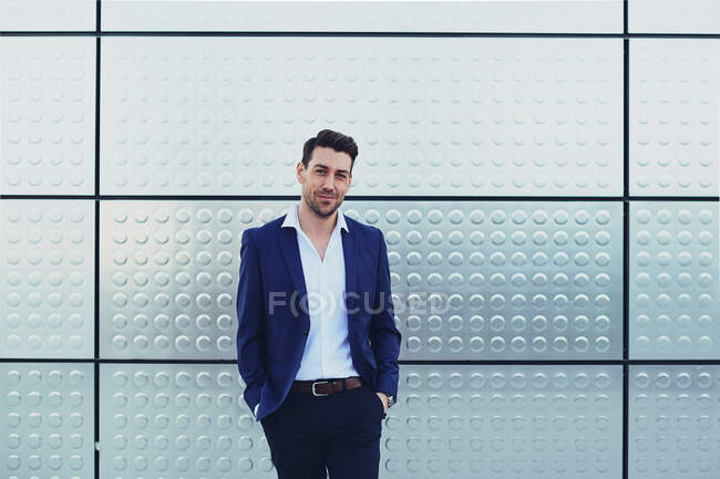 Selbstbewusster männlicher Unternehmer in formeller Kleidung mit den Händen in den Taschen, die in die Kamera schauen — Stockfoto
