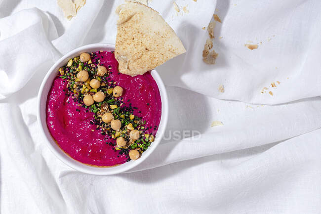 Von oben appetitanregender Rote-Bete-Hummus garniert mit Kichererbsen, serviert auf Stoffhintergrund mit Brot — Stockfoto