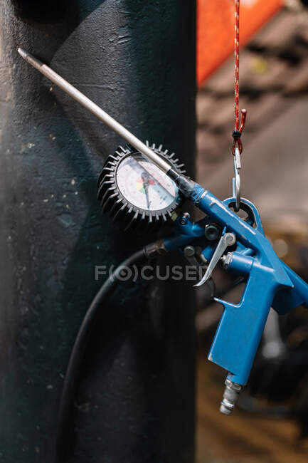 Pistola di gonfiaggio pneumatici con manometro appeso vicino alla parete in officina di riparazione di biciclette shabby — Foto stock