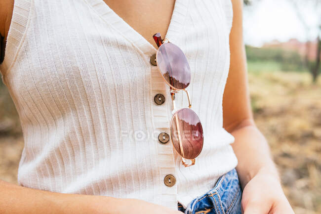Vista laterale di una donna anonima con gli occhiali da sole appesi alla camicia — Foto stock