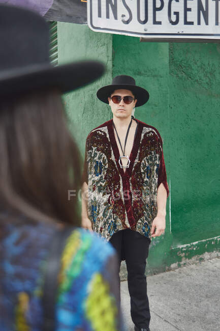 Неузнаваемая девушка в модном наряде и стильном парне в шляпе и солнцезащитных очках, стоящих на городской улице — стоковое фото