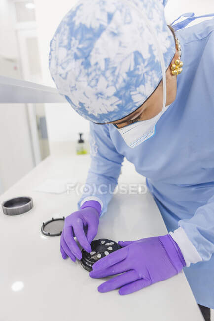 Crop anonymous female dentist with tool preparing veneers for procedure in clinic — Stock Photo