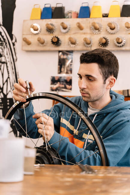 A roda de fixação mecânica masculina séria falou enquanto estava sentado na bancada no serviço de bicicleta — Fotografia de Stock