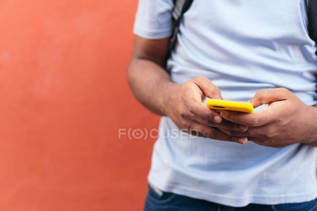 Hombre africano con teléfono inteligente junto a una pared roja - foto de stock