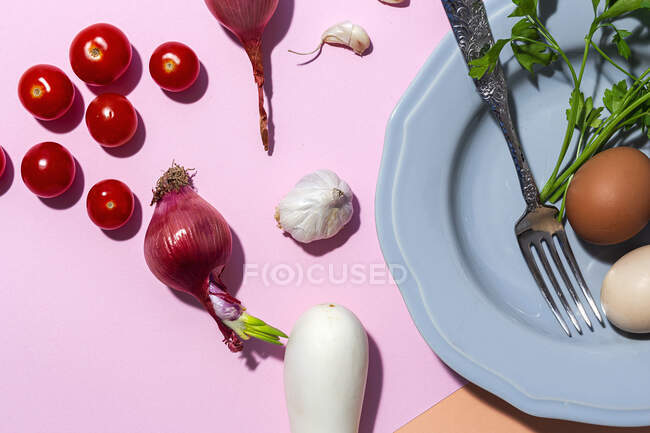 Top view of chicken eggs on plate with fork against fresh parsley sprigs and cherry tomatoes on two color background — Stock Photo