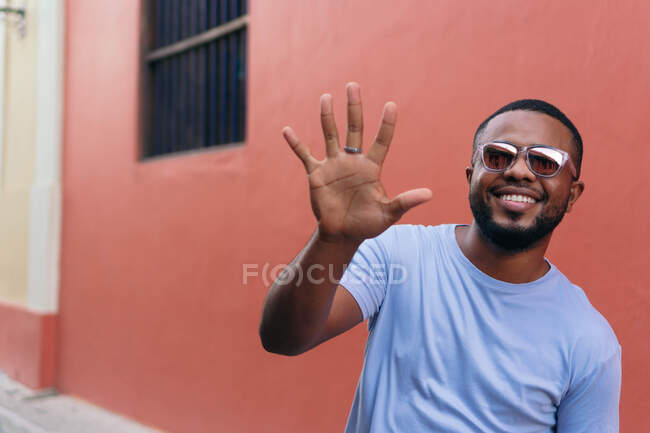 Усміхнений африканець показує свою руку, коли ходить у відкритому повітрі. — стокове фото