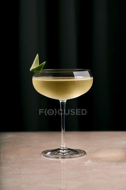 Элегантный хрустальный бокал шампанского, украшенный ломтиком лайма, подаваемый на мраморном столике в ресторане — стоковое фото