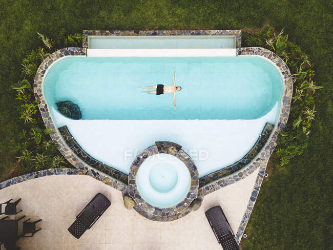 Top vue homme seul dans une piscine profitant d'une journée d'été ensoleillée — Photo de stock