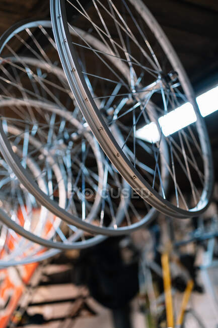 Von unten hängen metallglänzende Fahrradfelgen im Reparaturservice auf dem Gepäckträger — Stockfoto
